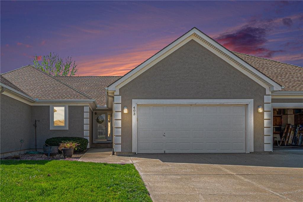 ranch-style home featuring concrete driveway, stucco siding, roof with shingles, and an attached garage