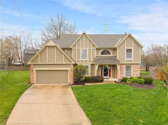 view of front facade with fence, brick siding, stucco siding, a front yard, and driveway