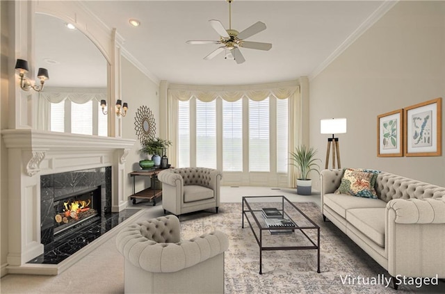 living area featuring ceiling fan, a premium fireplace, and crown molding