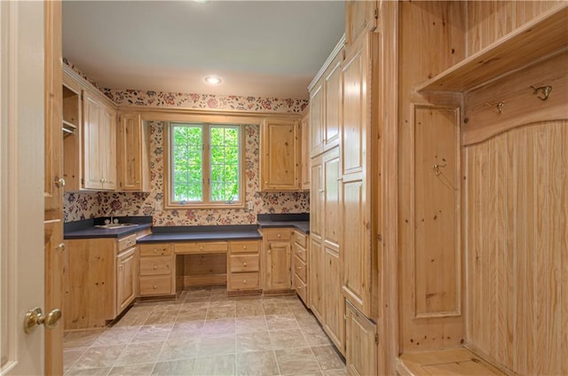 kitchen featuring dark countertops, light brown cabinetry, and a sink