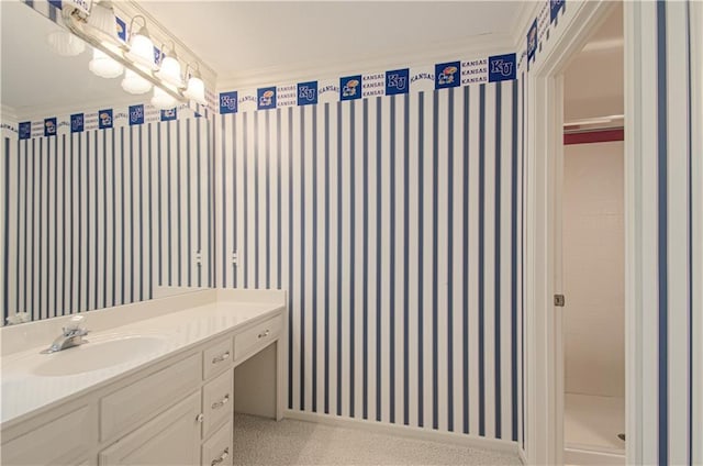 bathroom with vanity, wallpapered walls, crown molding, and a shower