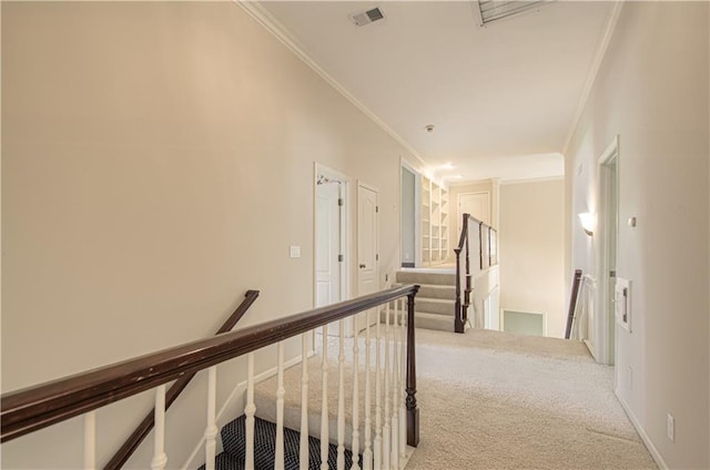 corridor with an upstairs landing, ornamental molding, and carpet