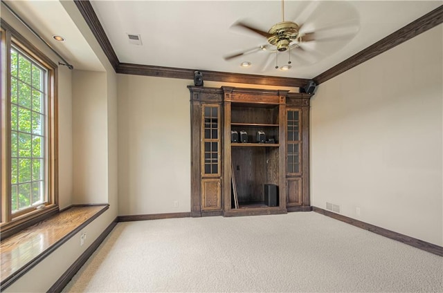 unfurnished living room featuring ornamental molding, a ceiling fan, baseboards, and light carpet