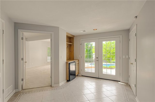 doorway with french doors, light tile patterned flooring, baseboards, and inlaid floor details