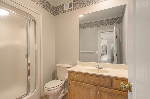bathroom with a shower stall, toilet, vanity, and ornamental molding