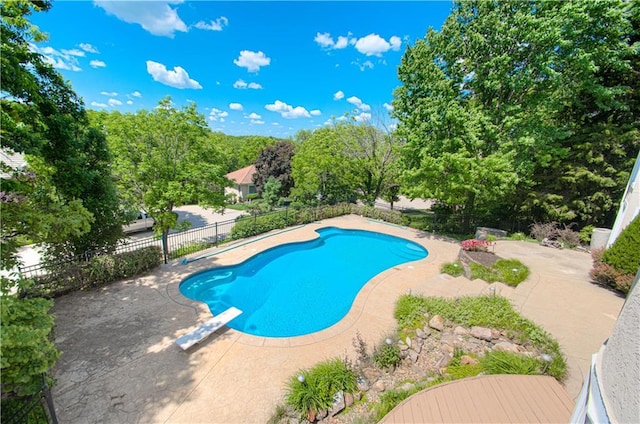 view of swimming pool with a diving board, fence, and a patio area