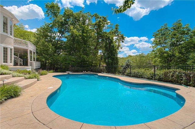 view of pool with fence, a patio, and view of scattered trees