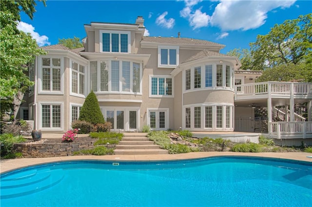 back of house with french doors, an outdoor pool, stucco siding, and a chimney