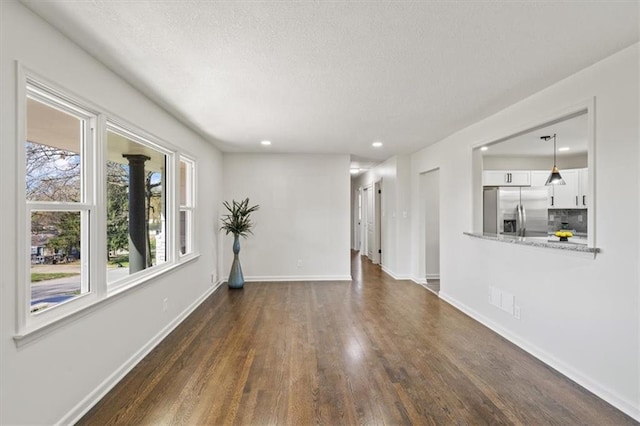 unfurnished living room with a textured ceiling, dark wood-style flooring, baseboards, and recessed lighting