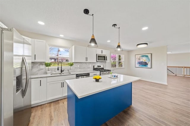 kitchen featuring a center island, a sink, light wood-type flooring, stainless steel appliances, and backsplash