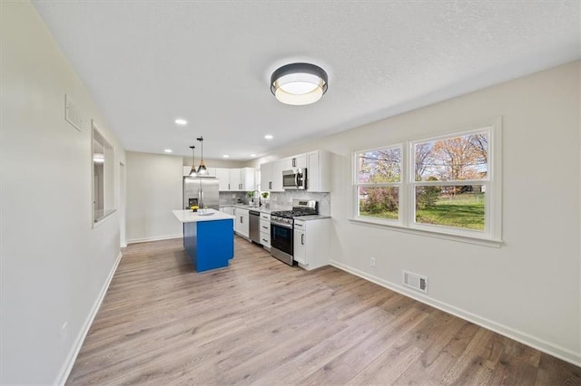 kitchen featuring visible vents, baseboards, light wood-style floors, white cabinetry, and stainless steel appliances