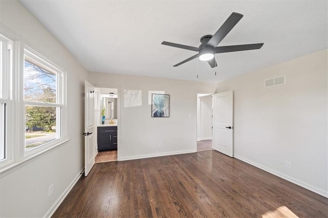 spare room featuring dark wood-type flooring, visible vents, baseboards, and a ceiling fan