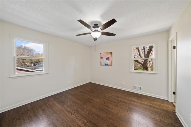 empty room with plenty of natural light, visible vents, baseboards, and wood finished floors