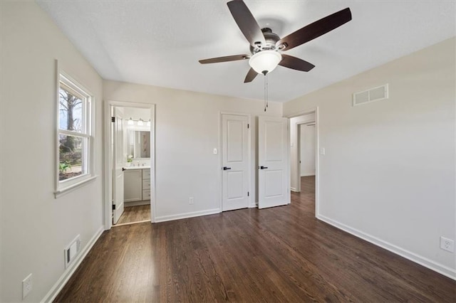 unfurnished bedroom featuring visible vents, baseboards, ensuite bath, and wood finished floors