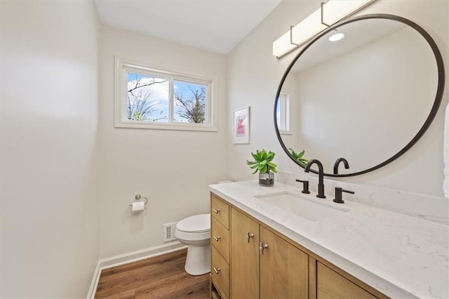 bathroom with vanity, baseboards, toilet, visible vents, and wood finished floors