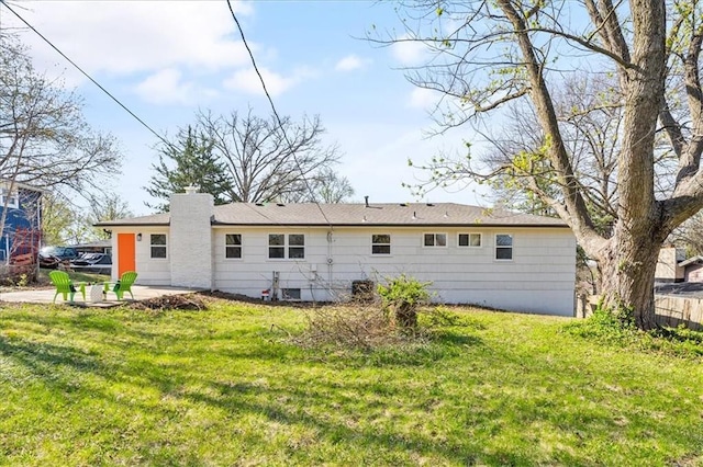rear view of property featuring fence, a patio, a lawn, and a chimney