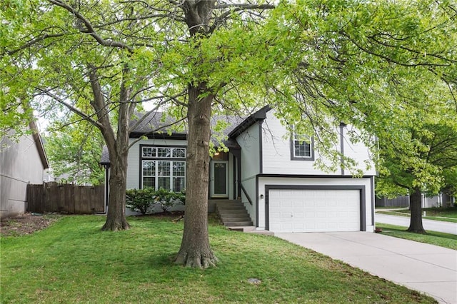 tri-level home with fence, an attached garage, concrete driveway, and a front lawn