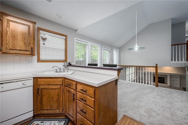 kitchen featuring vaulted ceiling, brown cabinets, dishwasher, a sink, and a peninsula