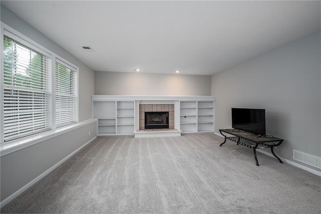 unfurnished living room featuring carpet flooring, baseboards, visible vents, and a tiled fireplace