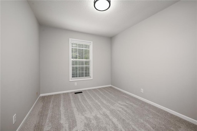 carpeted empty room with baseboards, a textured ceiling, and visible vents