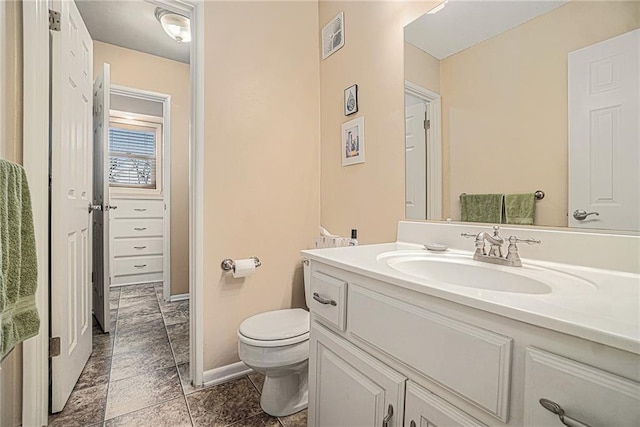 bathroom featuring baseboards, visible vents, toilet, and vanity