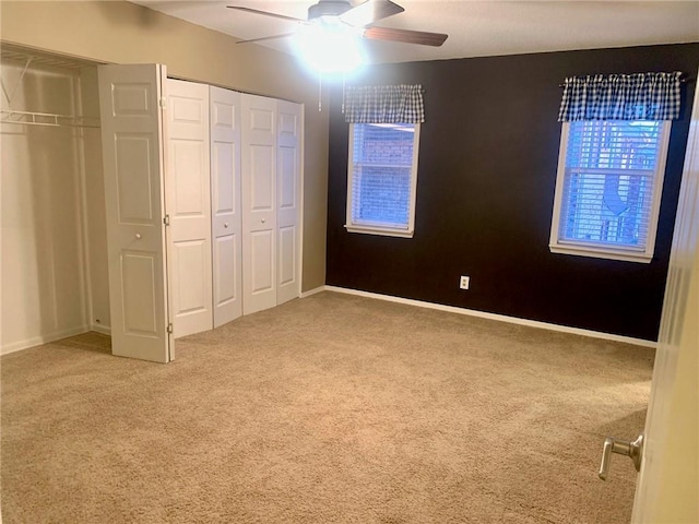 unfurnished bedroom with baseboards, carpet floors, ceiling fan, and two closets