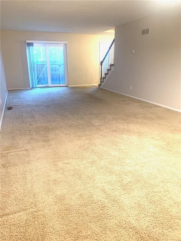 carpeted spare room featuring baseboards, stairs, and visible vents
