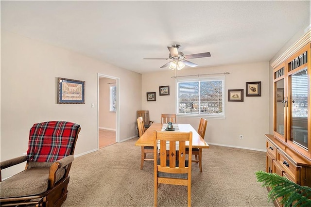 carpeted dining area featuring baseboards, a healthy amount of sunlight, and ceiling fan
