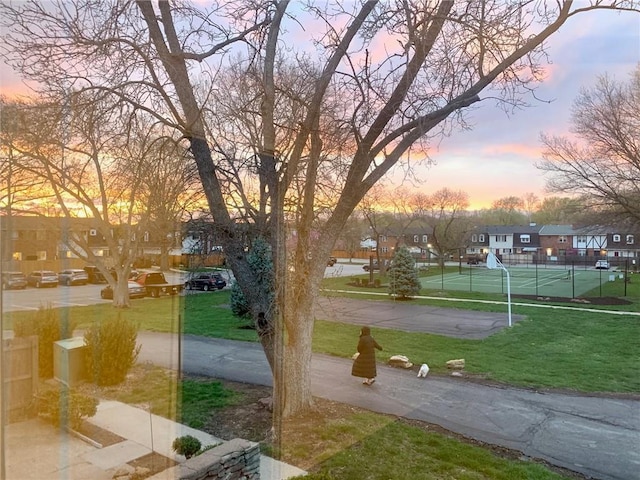 view of community featuring a residential view, a tennis court, and a yard