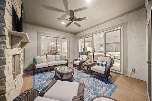 2189 W 89th Pl, Leawood, KS 66206 - living room featuring a textured wall, ceiling fan, a stone fireplace, and wood finished floors