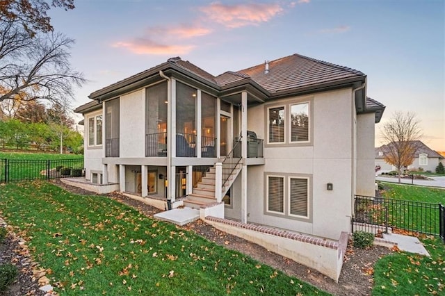 2189 W 89th Pl, Leawood, KS 66206 - back of property at dusk featuring stucco siding, stairway, a sunroom, a tiled roof, and fence
