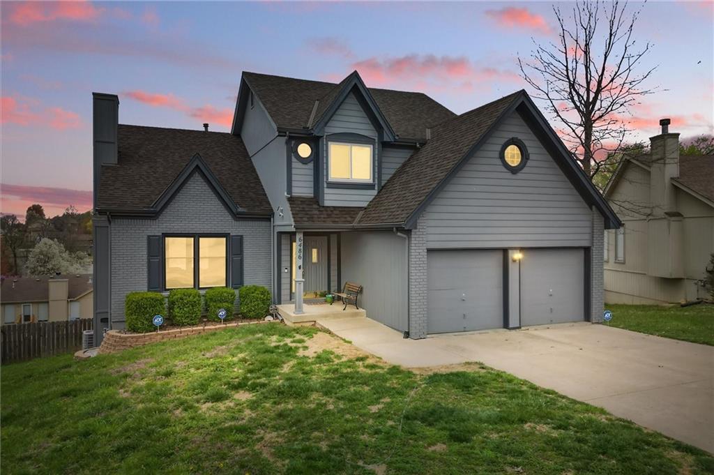 traditional home featuring a front yard, concrete driveway, and a shingled roof