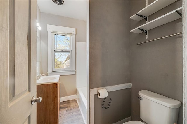 full bath featuring vanity, baseboards, toilet, a washtub, and wood finished floors