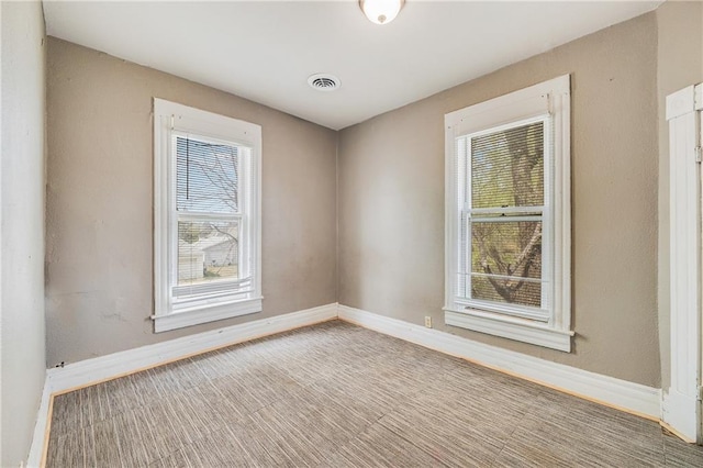 carpeted spare room featuring visible vents and baseboards