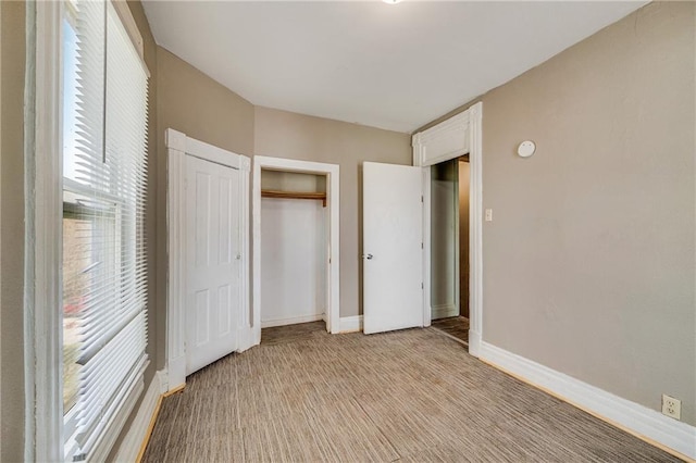 unfurnished bedroom featuring a closet, light colored carpet, and baseboards