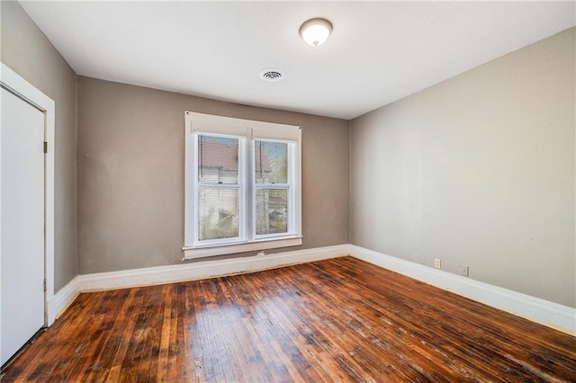 empty room with visible vents, baseboards, and hardwood / wood-style floors