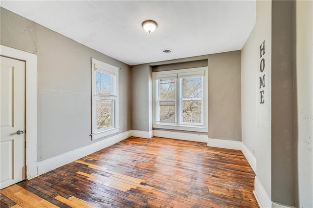 spare room featuring baseboards, wood-type flooring, and visible vents