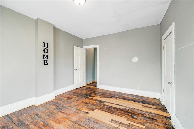 empty room with wood-type flooring and baseboards