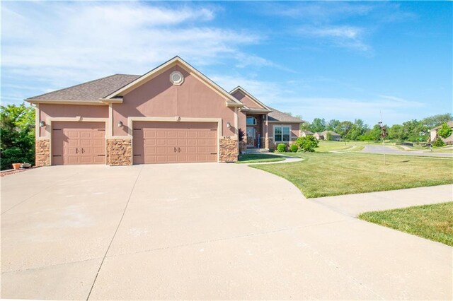 view of front facade featuring stone siding, a front yard, an attached garage, driveway, and stucco siding