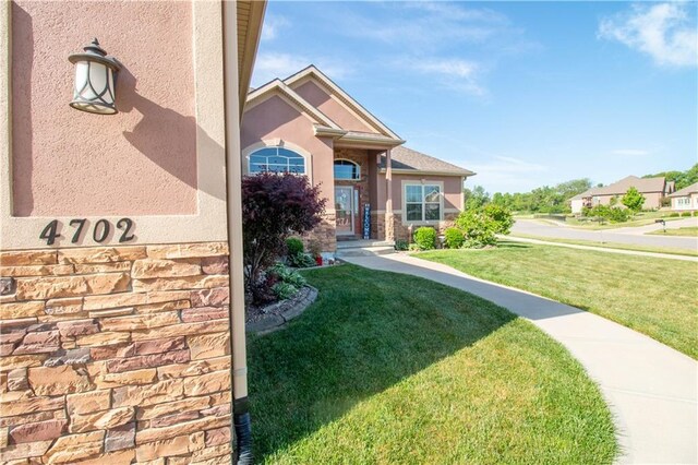 view of front of property with a front lawn, stone siding, and stucco siding