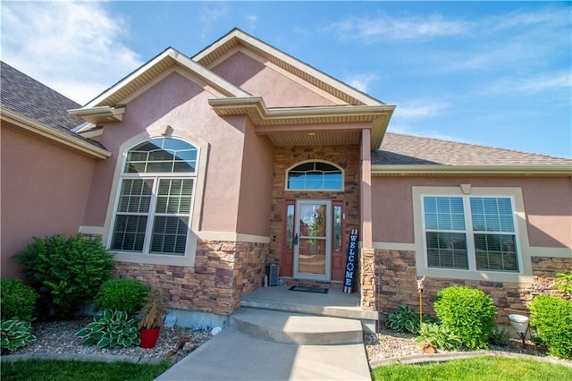 property entrance featuring stone siding, stucco siding, and a shingled roof