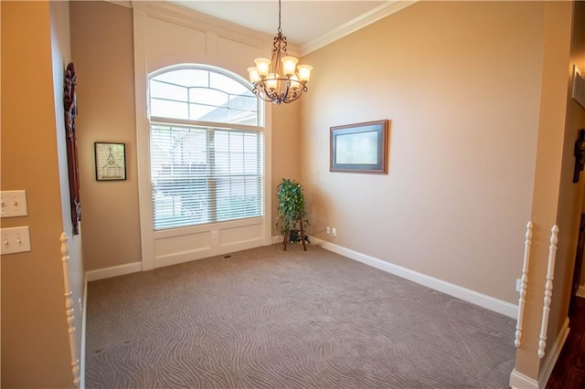 carpeted spare room featuring a chandelier, ornamental molding, and baseboards