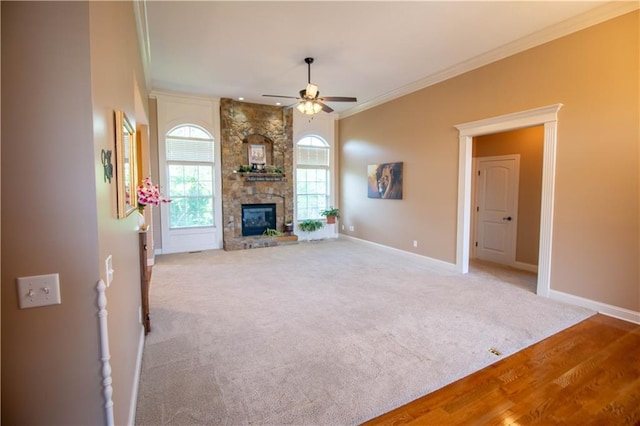 unfurnished living room with crown molding, ceiling fan, baseboards, a fireplace, and carpet floors