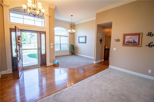 entryway with a chandelier, crown molding, carpet floors, wood finished floors, and baseboards