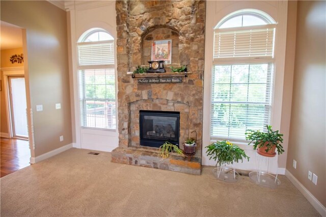 carpeted living room featuring healthy amount of natural light, a fireplace, and baseboards