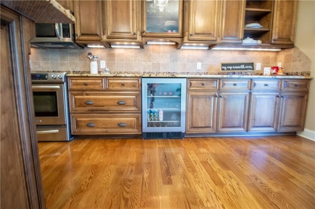 kitchen with beverage cooler, appliances with stainless steel finishes, brown cabinetry, and decorative backsplash