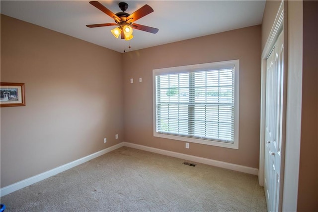 carpeted empty room featuring baseboards and a ceiling fan