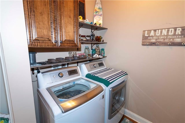 washroom with washing machine and dryer, cabinet space, and baseboards
