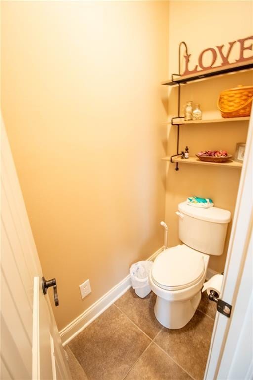 bathroom featuring tile patterned flooring, toilet, and baseboards