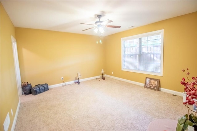 carpeted empty room with ceiling fan and baseboards